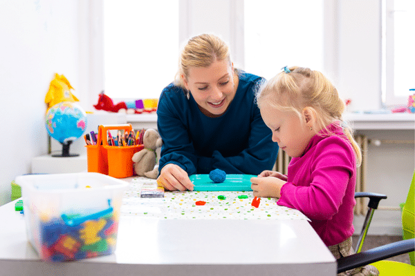 Photo d'une professionnelle aidant un enfant à manipuler de petites briques pour améliorer son écriture